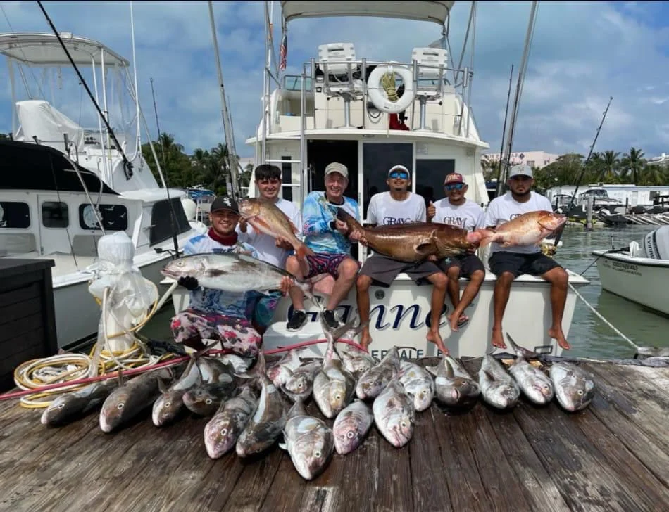 Group showing their catches beside a fishing boat