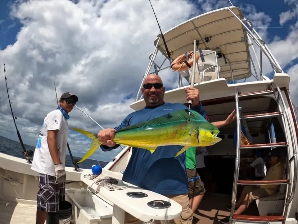 Angler with a dorado alongside the fishing boat